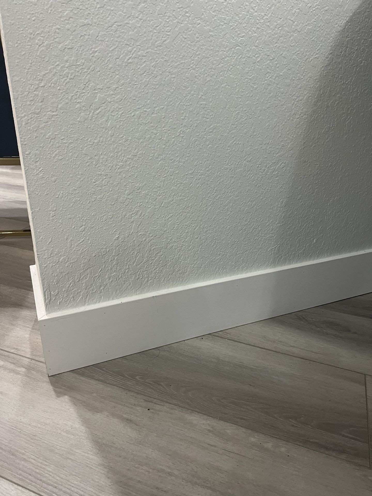 Modern white 1 x 6 baseboard installed along vinyl flooring