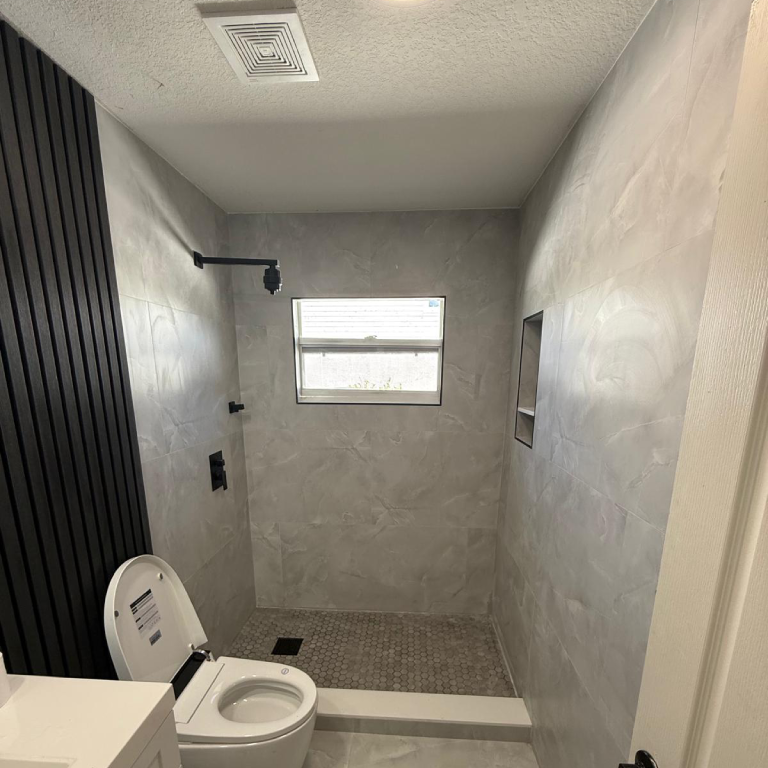 Finished bathroom with modern tile flooring and tiled shower walls