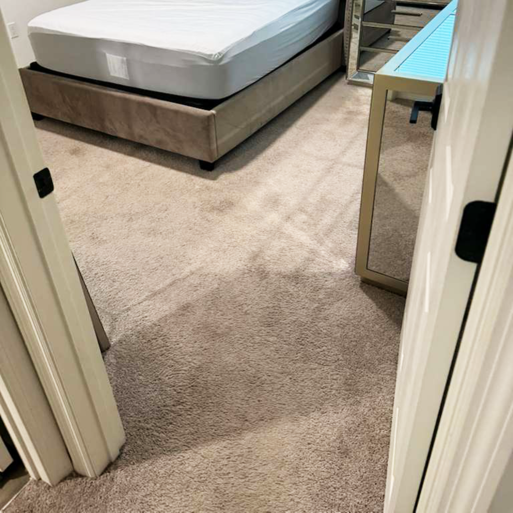 Bedroom carpet before vinyl upgrade Old beige carpet in a bedroom with a bed and mirrored furniture
