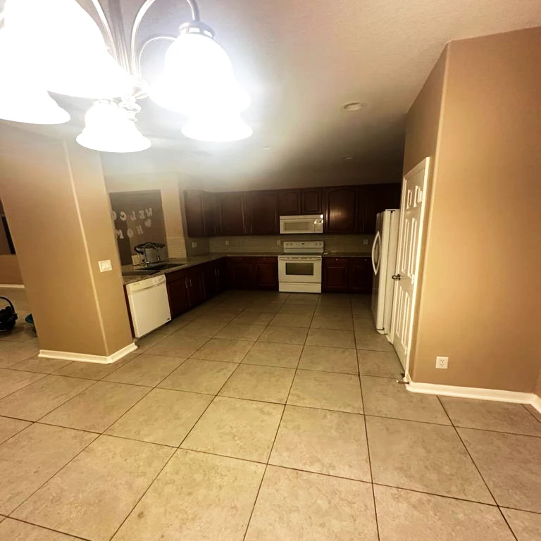 Original Kitchen State Before Rustic Pine Flooring Upgrade Kitchen interior before renovation with dated large square ceramic tiles and brown cabinetry