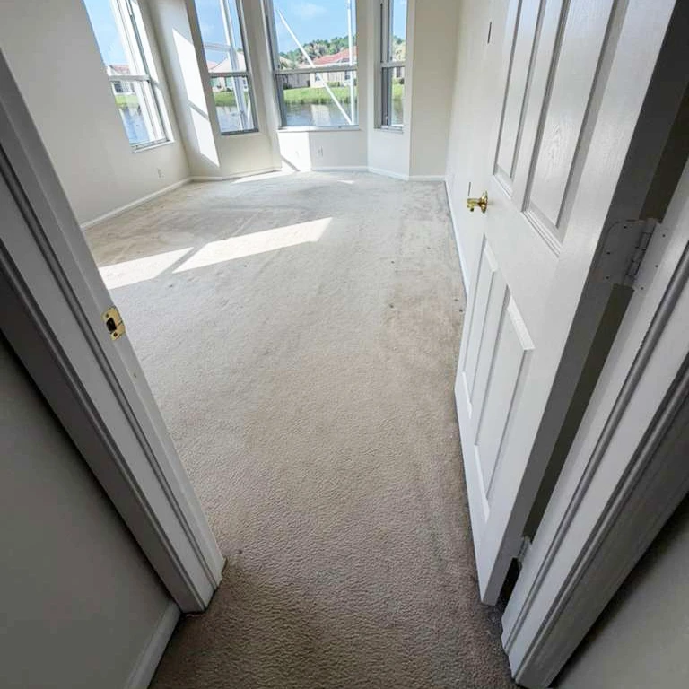 Bright bedroom with bay windows and worn beige carpet before renovation — ready for Waterproof Luxury Vinyl Plank 5.5mm installation in Sara Oak